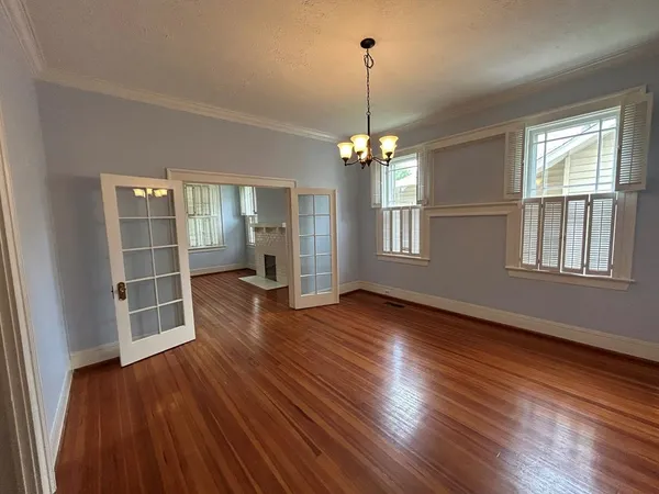 a view of an empty room with wooden floor fridge and a window