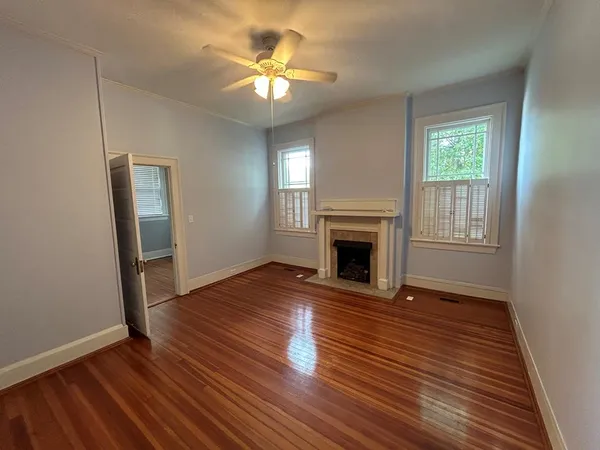 an empty room with wooden floor a fireplace and windows