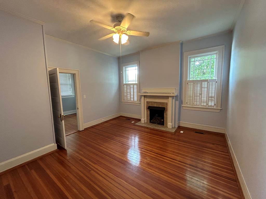 1192 Munro Avenue Columbus, GA 31906 - Photo 8 of 15 an empty room with wooden floor a fireplace and windows