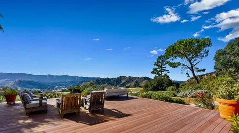 a view of a chairs and table on the wooden roof deck