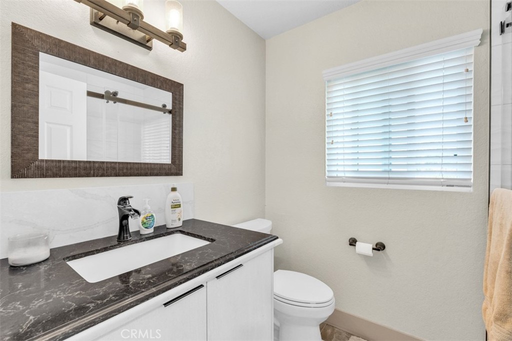 5056 Windhill Drive Riverside, CA 92507 - Photo 56 of 66 a bathroom with a granite countertop sink toilet and mirror