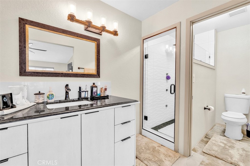 5056 Windhill Drive Riverside, CA 92507 - Photo 61 of 66 a bathroom with a granite countertop sink a toilet and a mirror