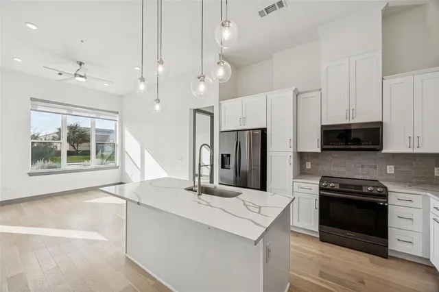 a kitchen with stainless steel appliances kitchen island a stove a sink and a refrigerator with wooden floor