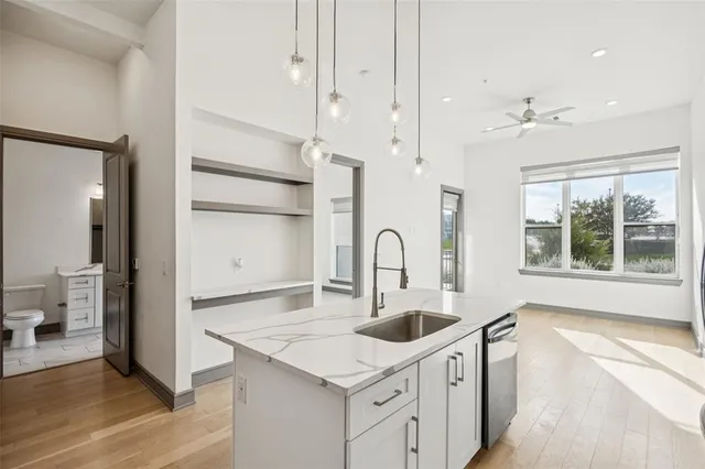 a kitchen with white cabinets a sink dishwasher and a stove with wooden floor