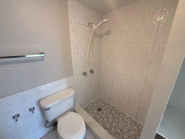 a white toilet sitting next to a shower