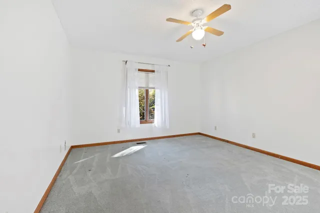 an empty room with a window and a ceiling fan