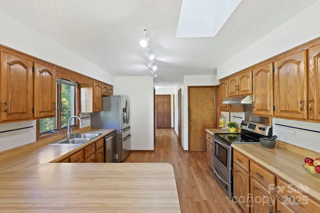 a large kitchen with stainless steel appliances granite countertop a large window and wooden floors