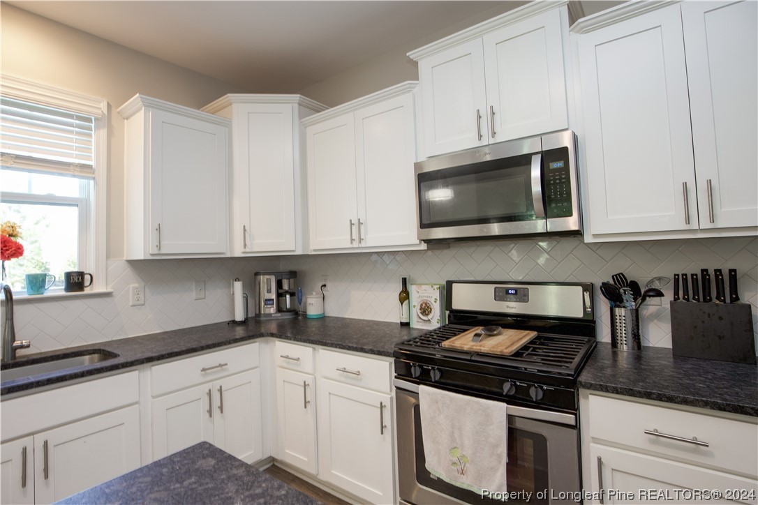 474 Kerr Lake Road Aberdeen, NC 28315 - Photo 15 of 47 a kitchen with stainless steel appliances granite countertop white cabinets granite counter tops and a wooden floors