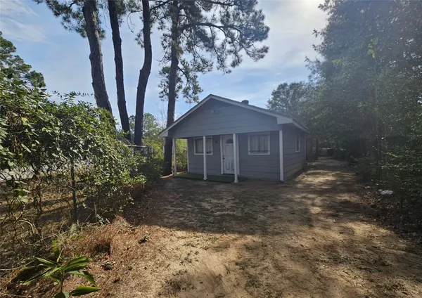 a front view of a house with a yard and large tree