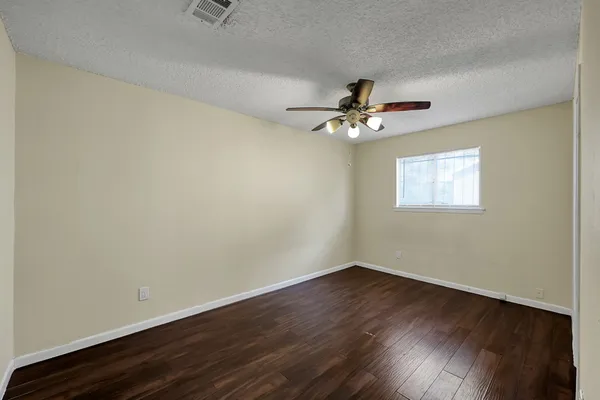 a view of a room with wooden floor and a ceiling fan