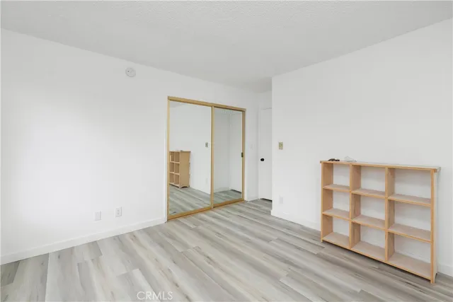 a view of an empty room with wooden floor and closet