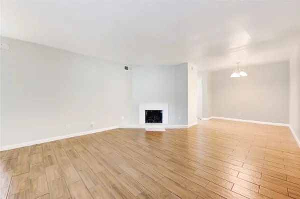 a view of an empty room with wooden floor and a fireplace