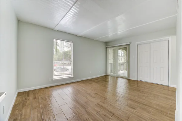 an empty room with wooden floor and windows