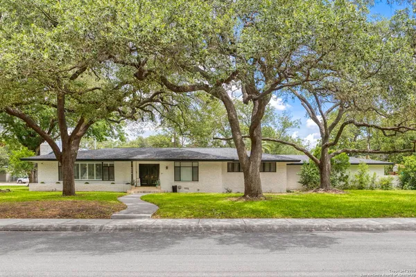 a front view of a house with a garden and trees