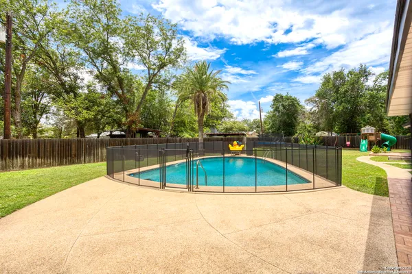 a view of a swimming pool with a patio and a yard