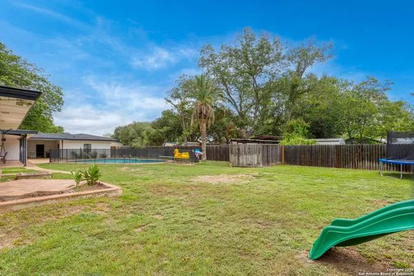 a view of a backyard with plants and wooden fence