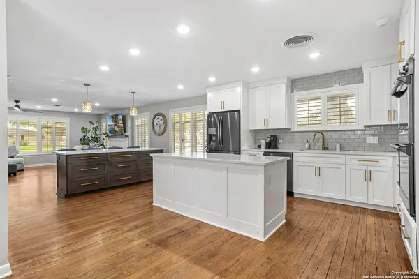 a kitchen with stainless steel appliances wooden floors and white cabinets