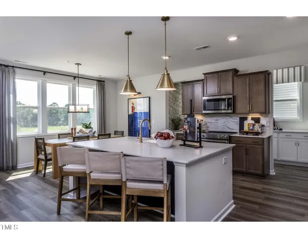 a kitchen with kitchen island granite countertop a sink cabinets and wooden floor