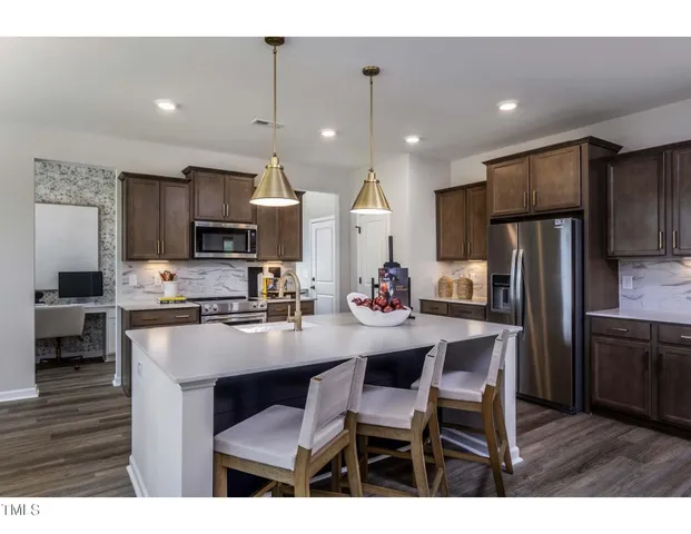 a kitchen with refrigerator a sink and chairs