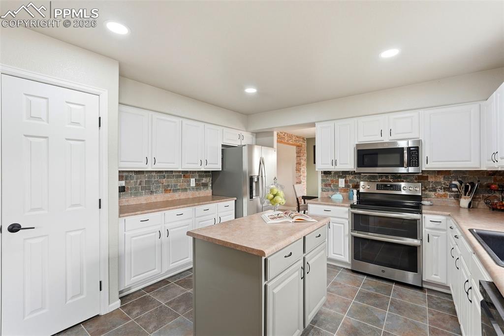 6907 Shimmering Leaf Road Colorado Springs, CO 80908 - Photo 11 of 49 a kitchen with a sink white cabinets and stainless steel appliances
