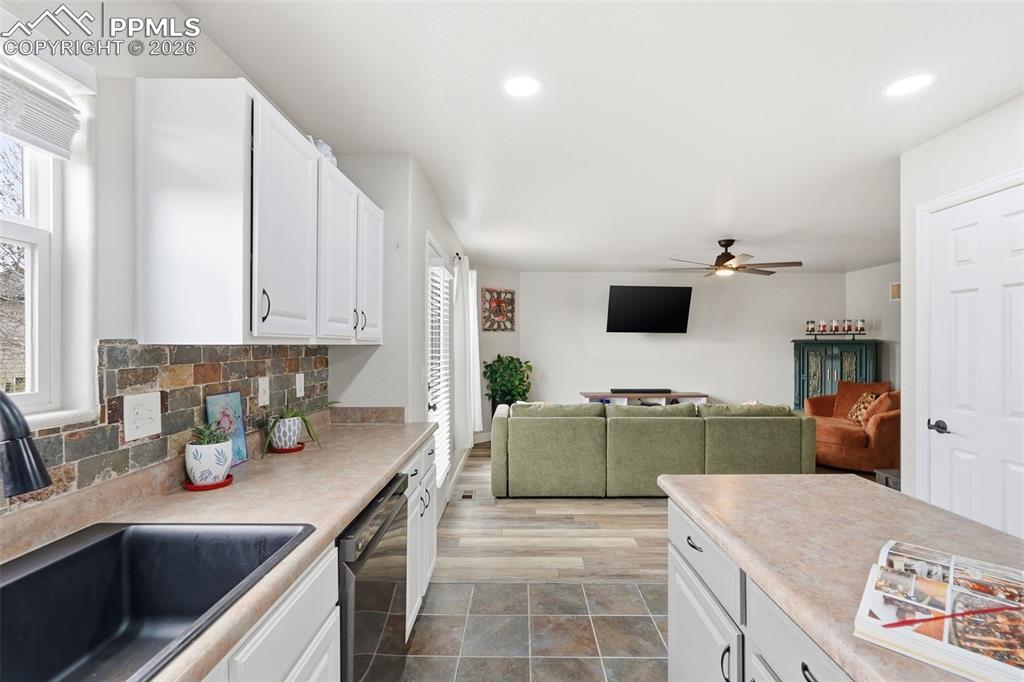 6907 Shimmering Leaf Road Colorado Springs, CO 80908 - Photo 14 of 49 a kitchen with a sink dishwasher stove and microwave with wooden floor