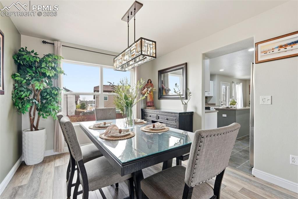 6907 Shimmering Leaf Road Colorado Springs, CO 80908 - Photo 7 of 49 a dining room with furniture a chandelier and wooden floor