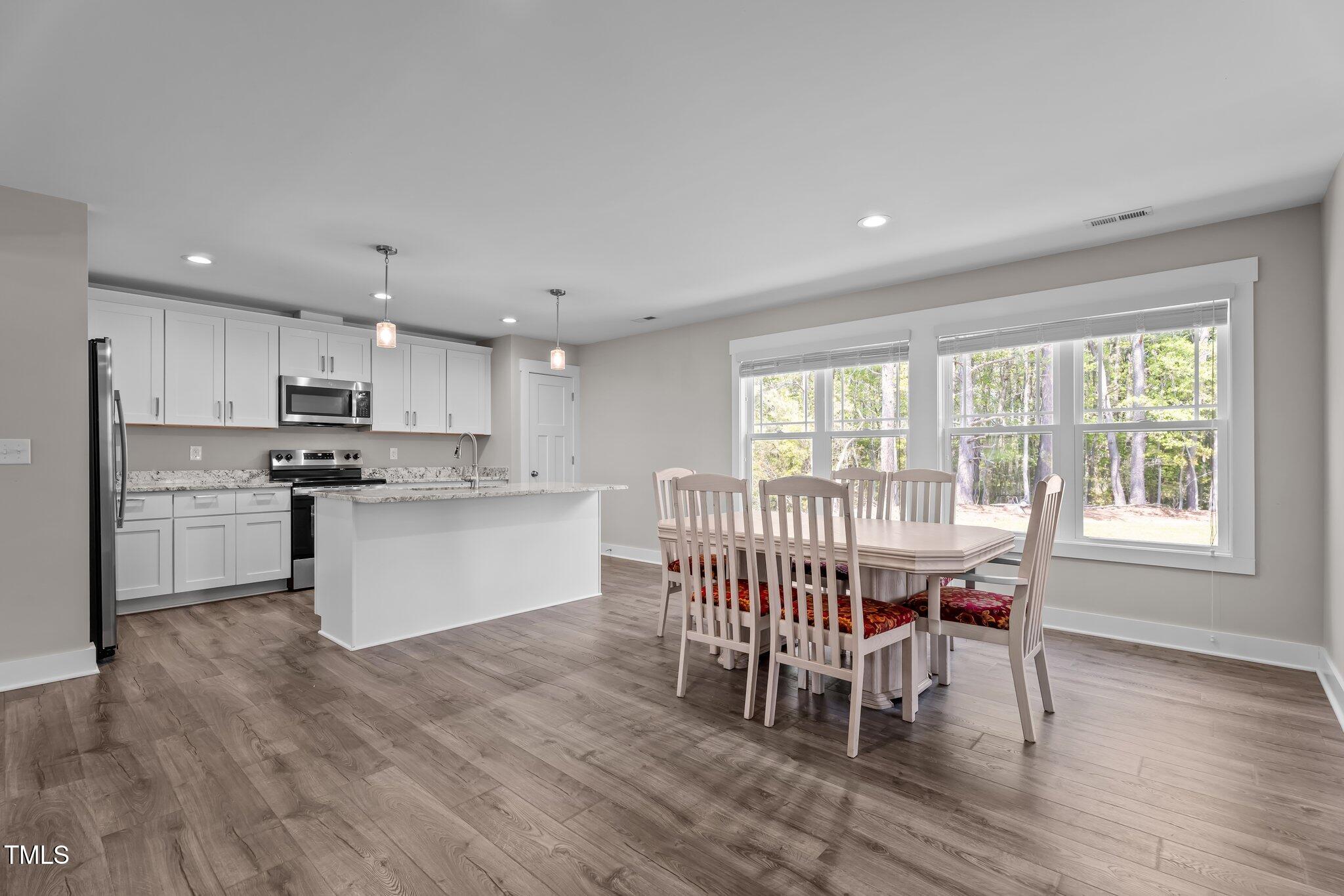 1914 Jack Road Clayton, NC 27520 - Photo 20 of 38 a kitchen with stainless steel appliances granite countertop a stove a sink a refrigerator dining table and chairs