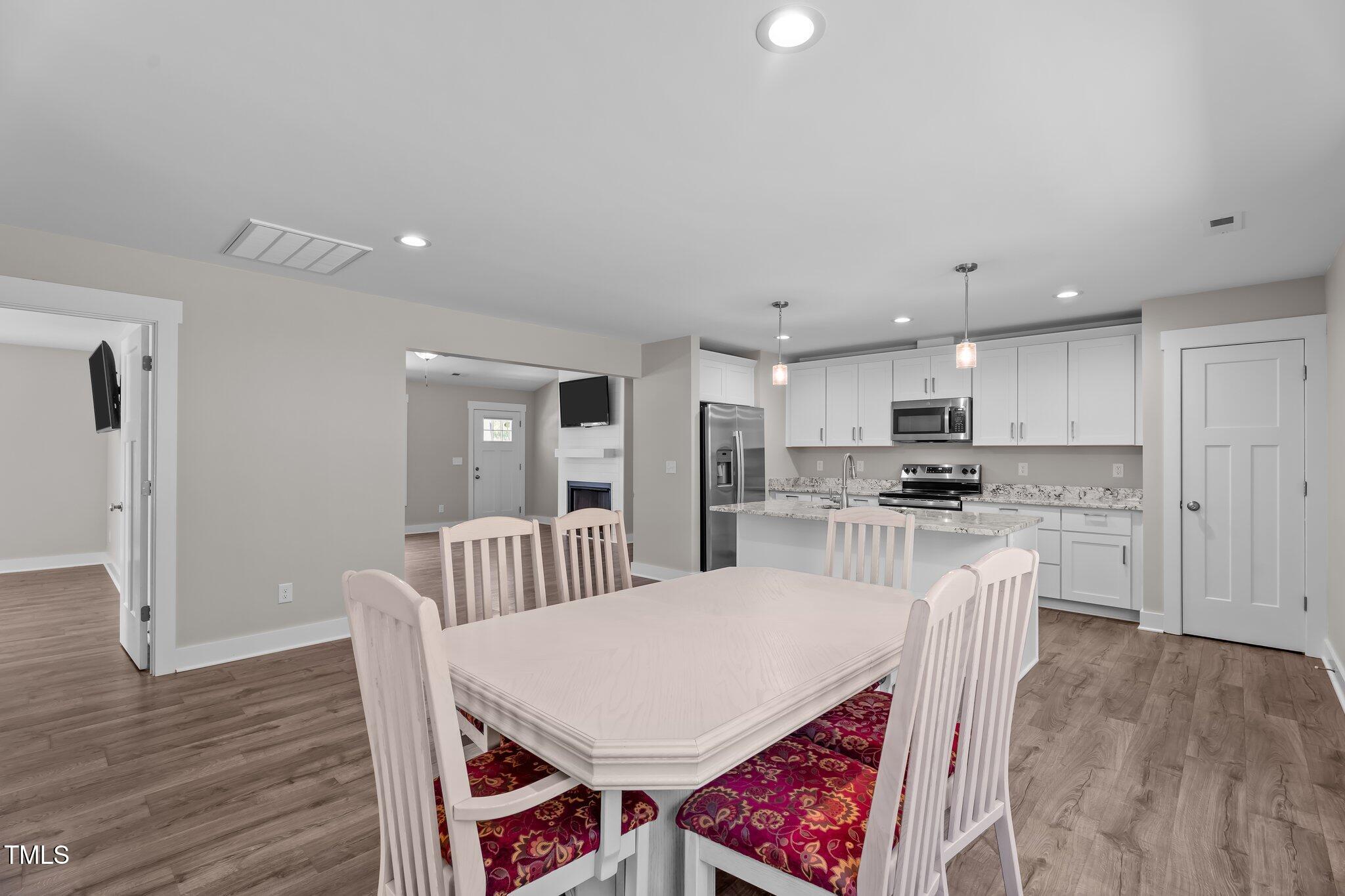 1914 Jack Road Clayton, NC 27520 - Photo 21 of 38 a kitchen with stainless steel appliances kitchen island granite countertop a stove a kitchen island a dining table and chairs with wooden floor