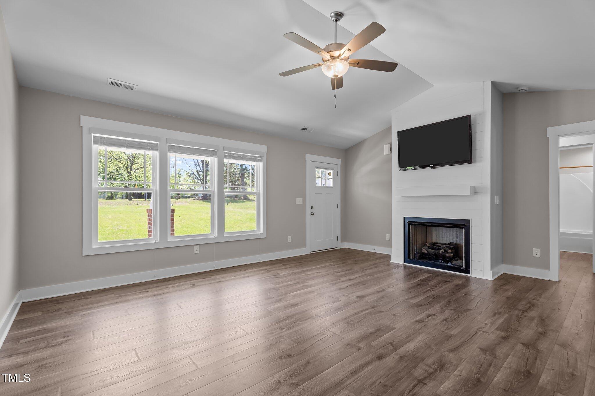 1914 Jack Road Clayton, NC 27520 - Photo 38 of 38 an empty room with windows fireplace and wooden floor