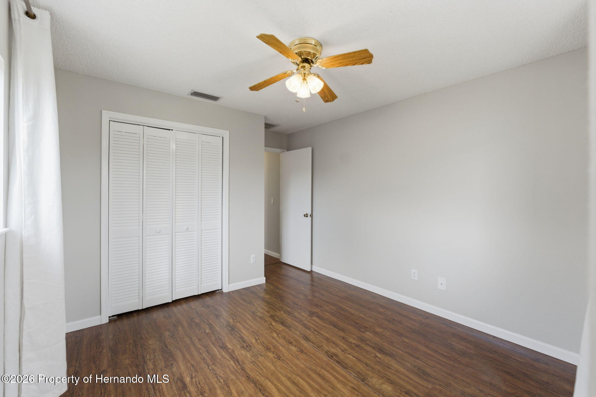 4966 Keysville Avenue Spring Hill, FL 34608 - Photo 38 of 50 a view of an empty room with wooden floor and a ceiling fan