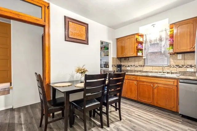 a kitchen with stainless steel appliances granite countertop a refrigerator a stove and a sink with wooden floor