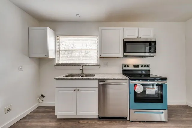 a kitchen with granite countertop a stove a microwave a sink and cabinets