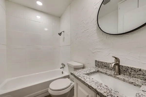 a bathroom with a granite countertop sink toilet a mirror and bathtub
