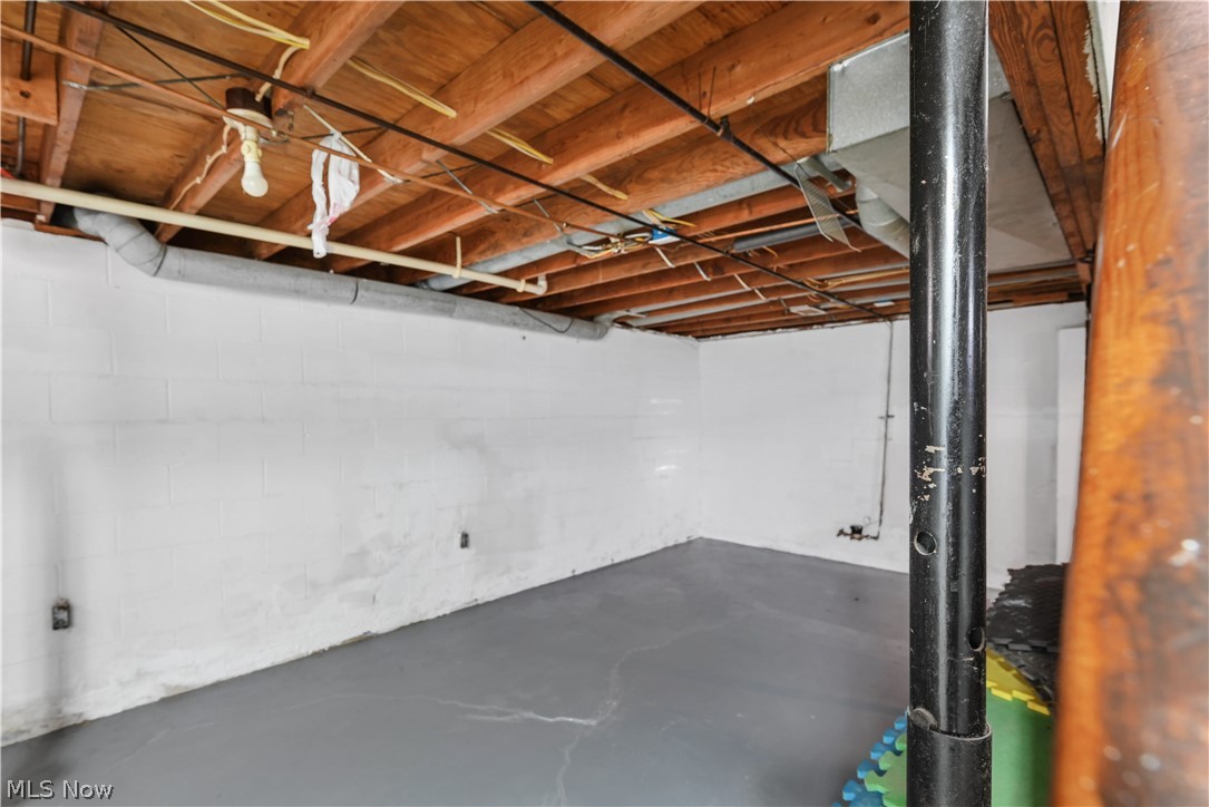 1286 Deforest Road Southeast Warren, OH 44484 - Photo 22 of 27 Unfinished basement space featuring exposed wooden ceiling joists, painted concrete block walls, and a painted concrete floor