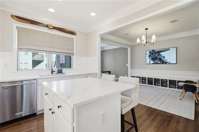 a living room with stainless steel appliances kitchen island a table chairs and chandelier