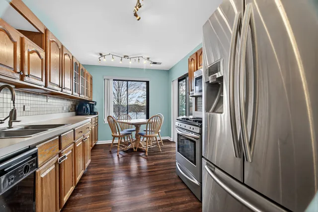 a kitchen with stainless steel appliances granite countertop a refrigerator a stove and a wooden floor