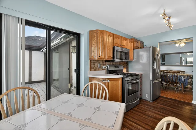 a kitchen with stainless steel appliances granite countertop a refrigerator a stove a sink a dining table and chairs