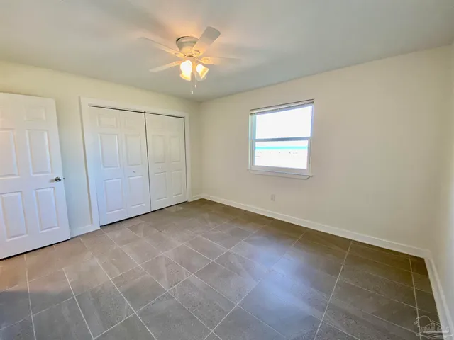 an empty room with windows and fan