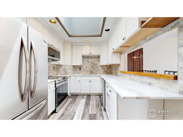 a kitchen with stainless steel appliances kitchen island granite countertop a sink refrigerator and cabinets