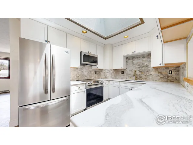 a kitchen with kitchen island a white cabinets and stainless steel appliances