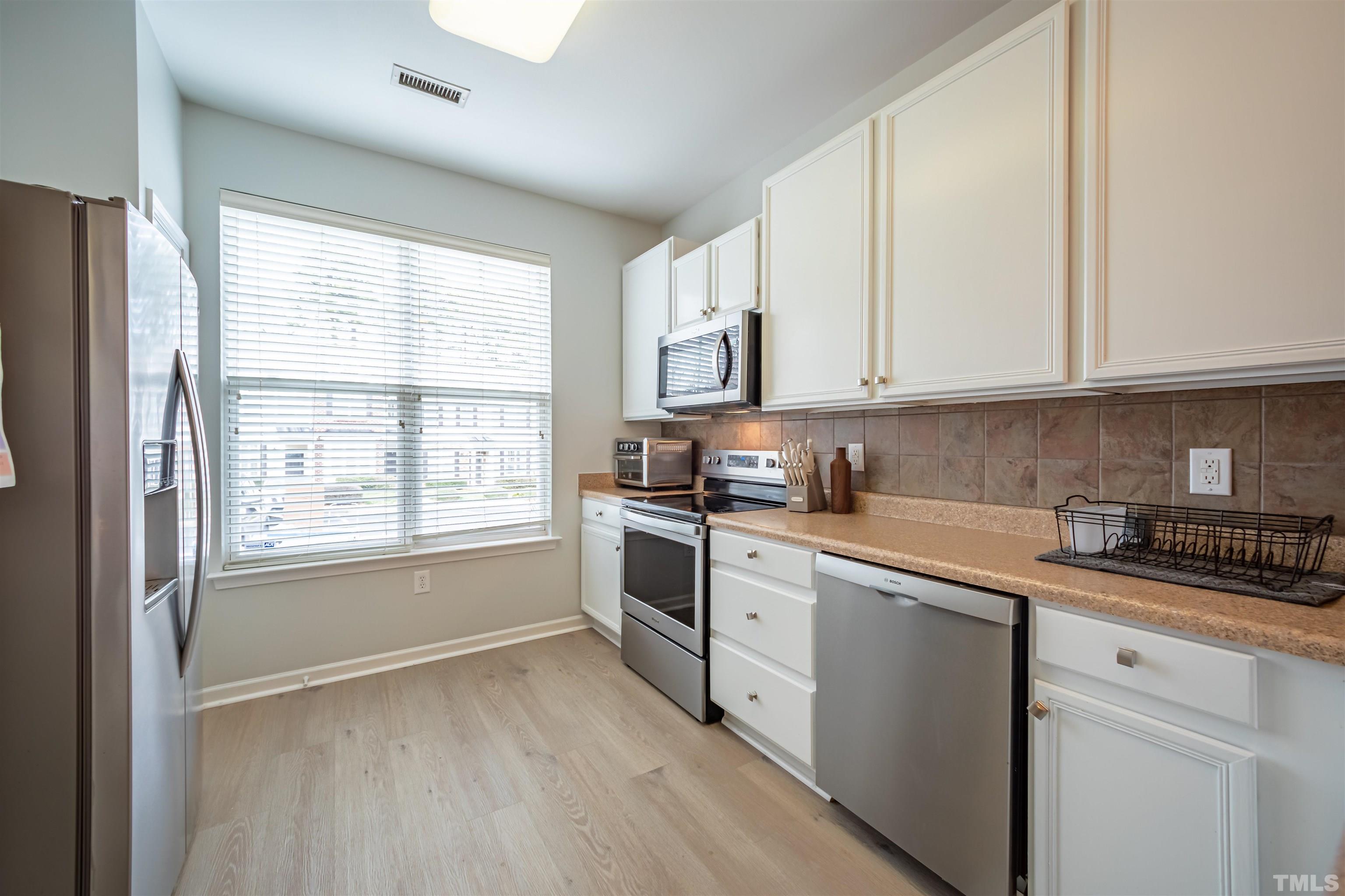 8447 Central Drive Raleigh, NC 27613 - Photo 5 of 19 a kitchen with stainless steel appliances granite countertop a stove a sink and white cabinets