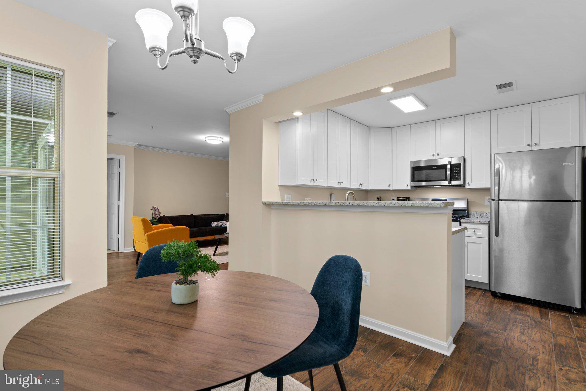 125 Timberbrook Lane, Unit T2 Gaithersburg, MD 20878 - Photo 11 of 30 a kitchen with stainless steel appliances granite countertop a dining table chairs a microwave a refrigerator and a dining table