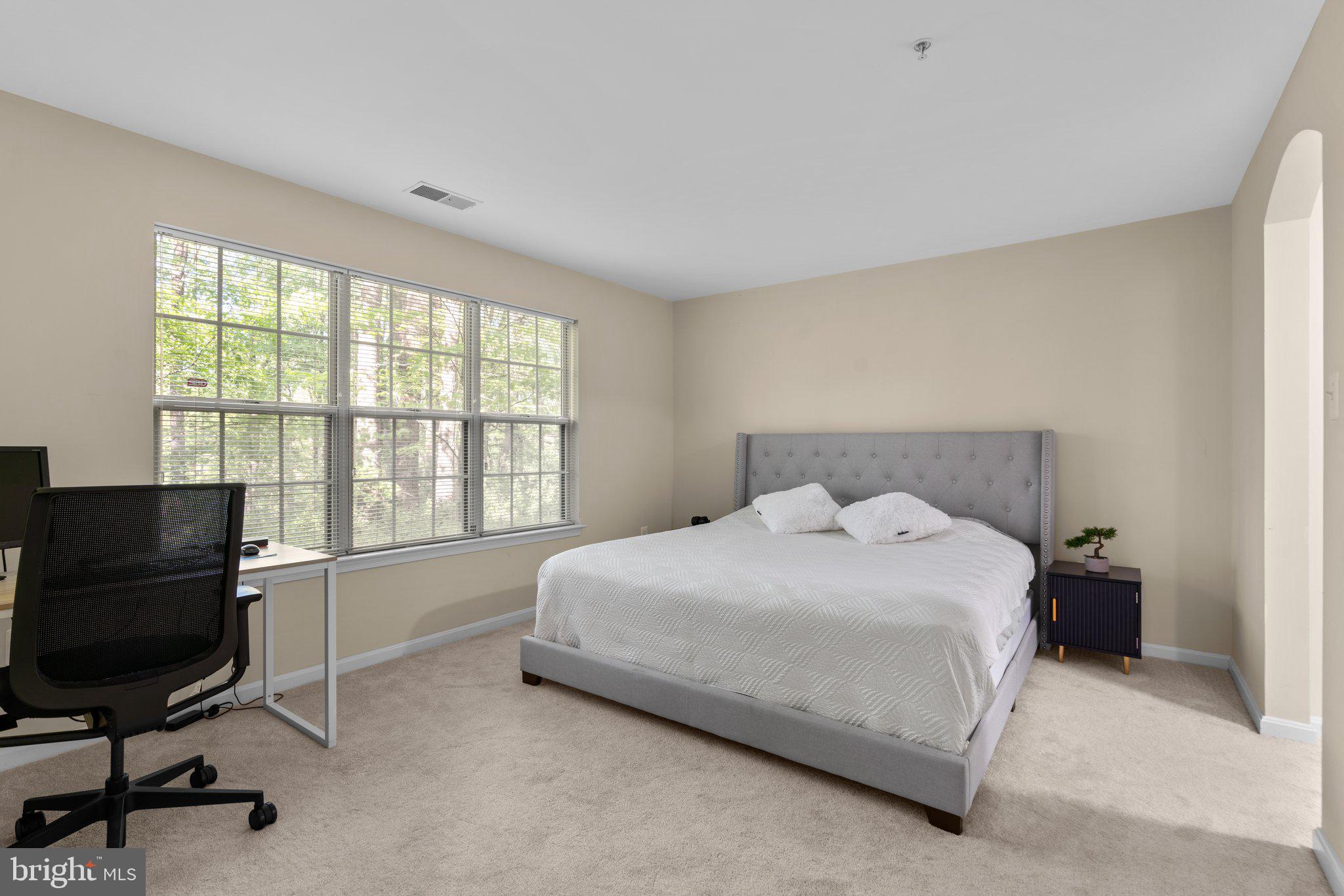 125 Timberbrook Lane, Unit T2 Gaithersburg, MD 20878 - Photo 18 of 30 a bedroom with a bed a chair and a computer on the desk next to a window