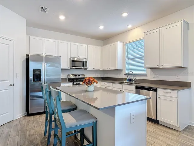 a kitchen with a sink a microwave a refrigerator and cabinets