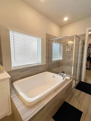 a bathroom with a tub a sink and a large window