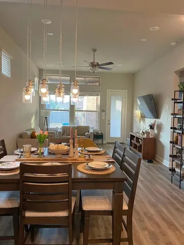 a dining room with wooden floor a chandelier a glass table and chairs