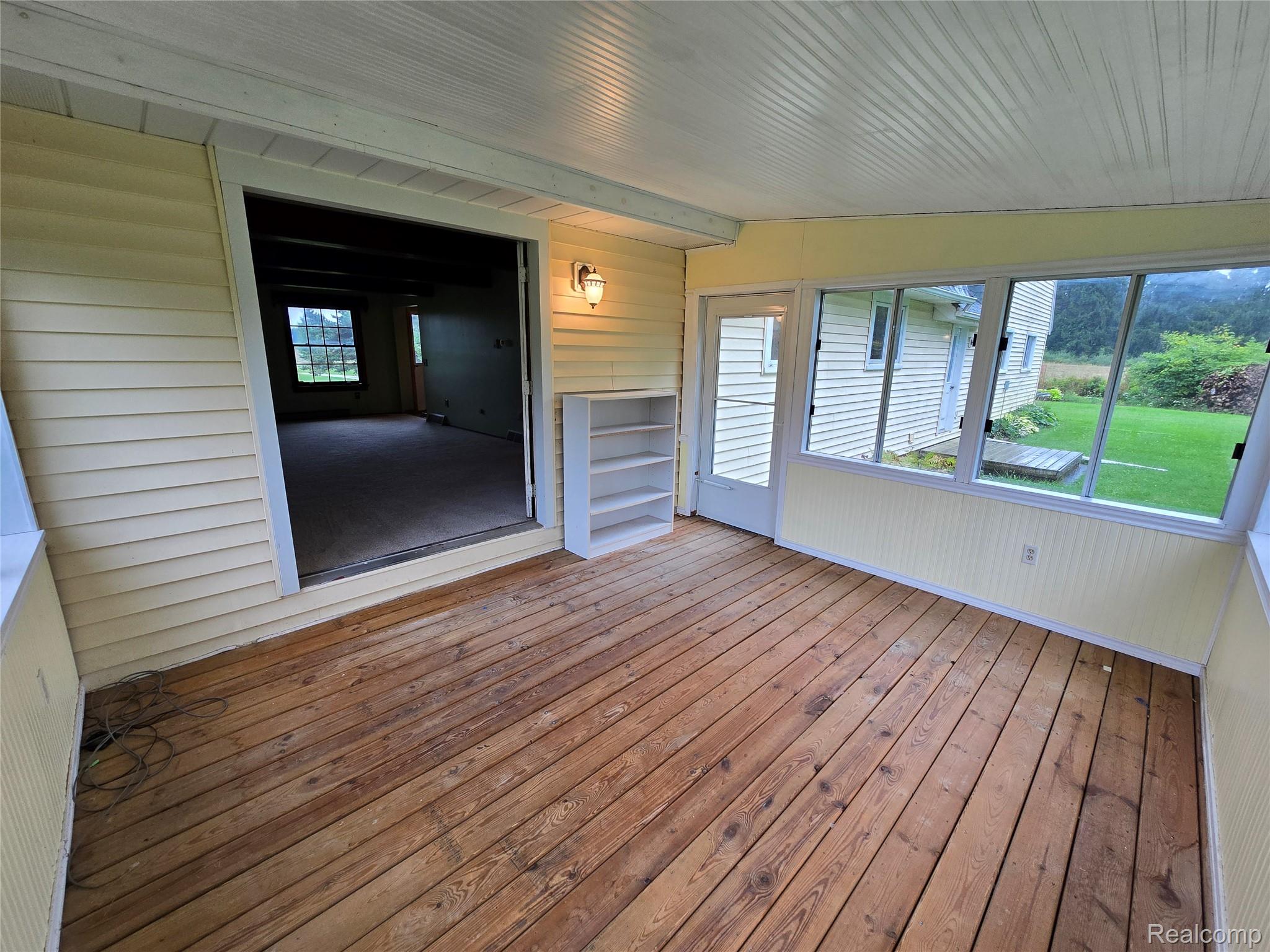 5282 McIntyre Road North Street, MI 48049 - Photo 16 of 53 Enclosed porch featuring wood plank flooring, a beadboard ceiling, multiple windows, and a glass-paneled door