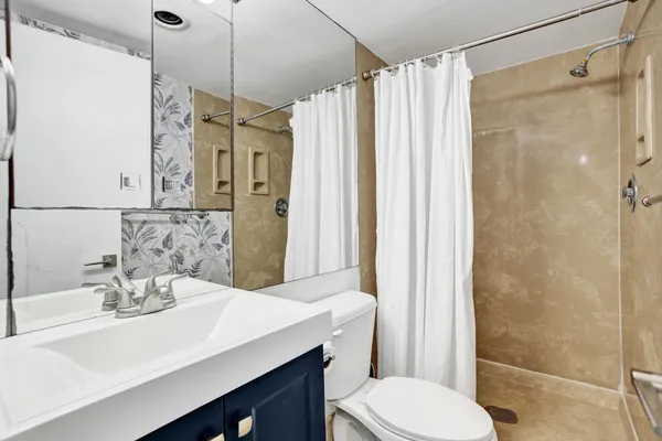 a bathroom with a sink a toilet a mirror and shower