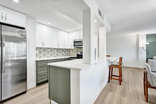 a kitchen with stainless steel appliances granite countertop a refrigerator a stove and a sink with wooden floor
