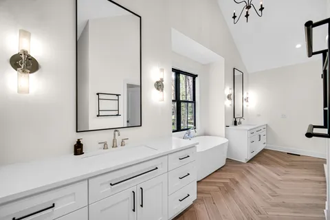 a spacious bathroom with a double vanity sink a mirror and a bathtub